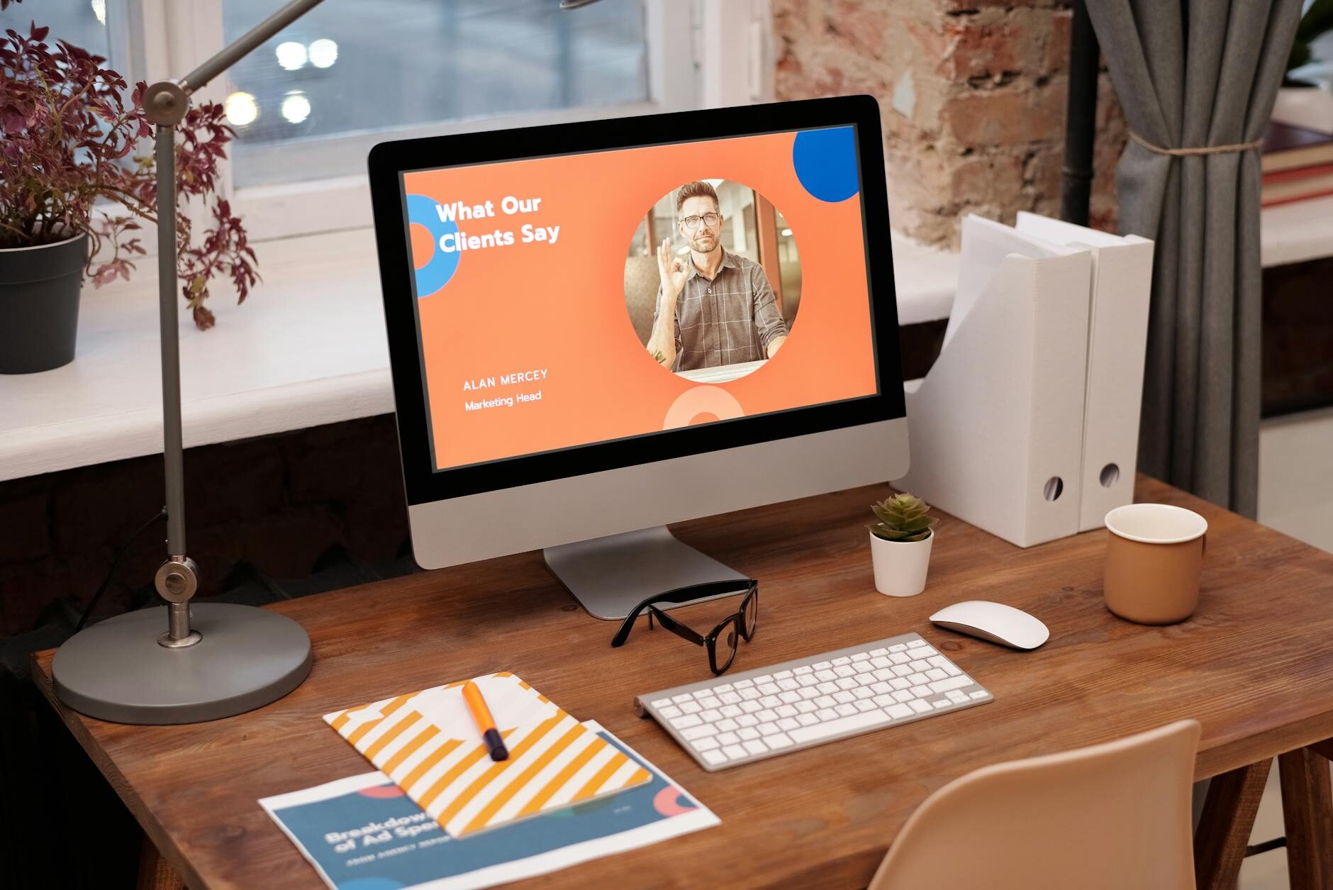 iMac displaying a colorful website design at a warm wooden desk with plants