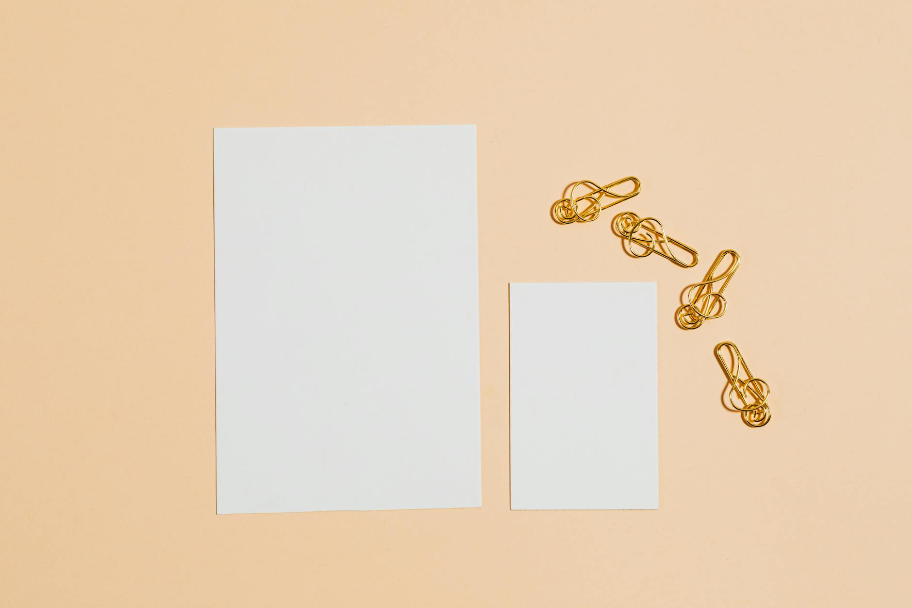 Stationery and business card on warm peach background with gold paper clips